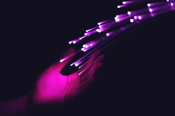 Colorful close up of hand touching optical fibers